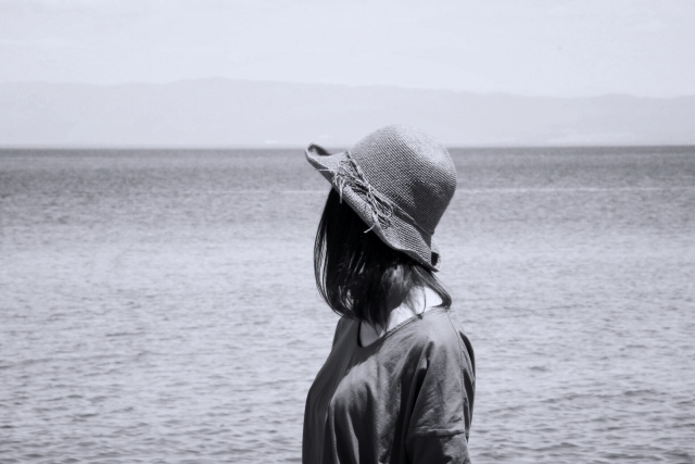 辛い時に海を眺めている帽子をかぶった女性の画像