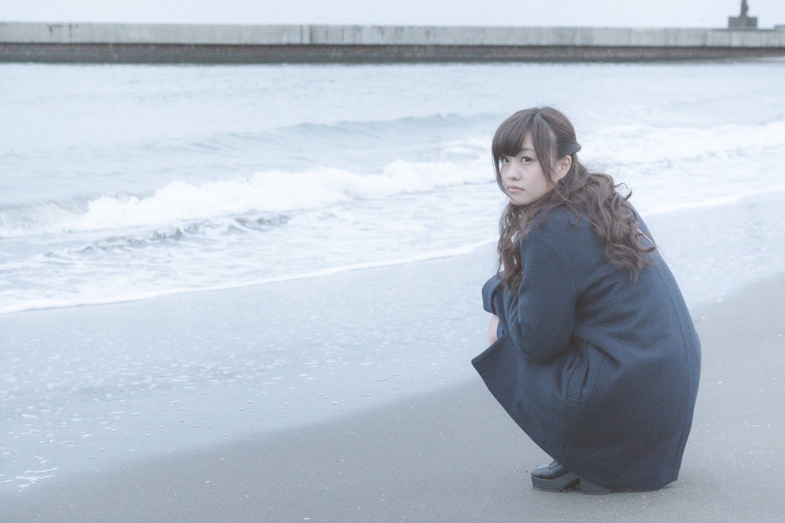 人生なんとかなると言いながら浜辺に座り込んでいる女性の画像