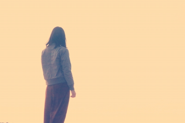 心から笑えなくなった女性が海を眺めている画像