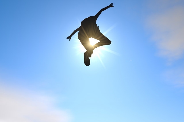 人生勝ち組だと叫びながら空高くジャンプしている男性の画像