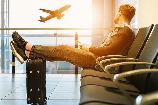 旅行に一緒に行く友達がいなくて一人で空港に来た男性の画像