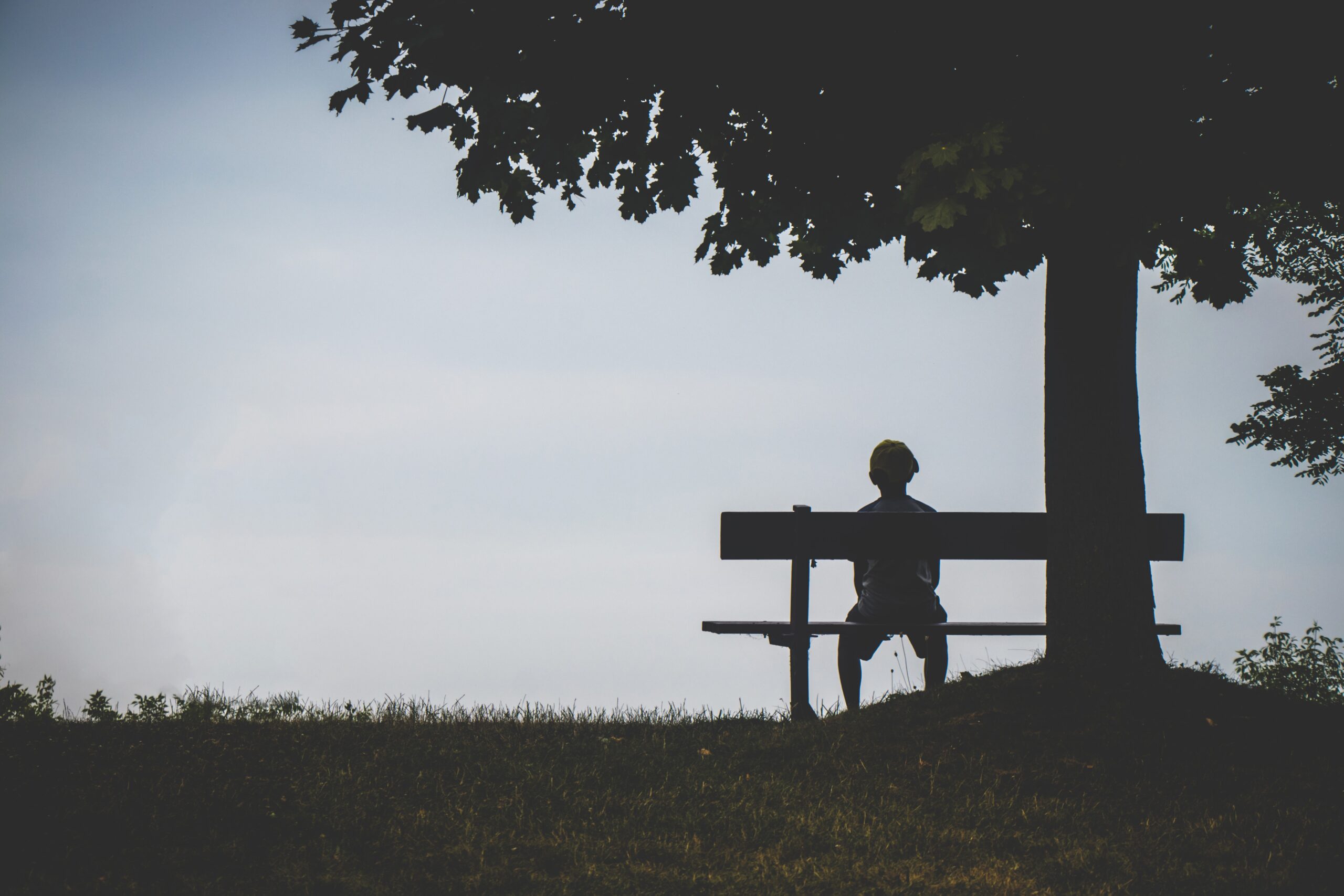人生に絶望を感じている男性がベンチに座っている画像