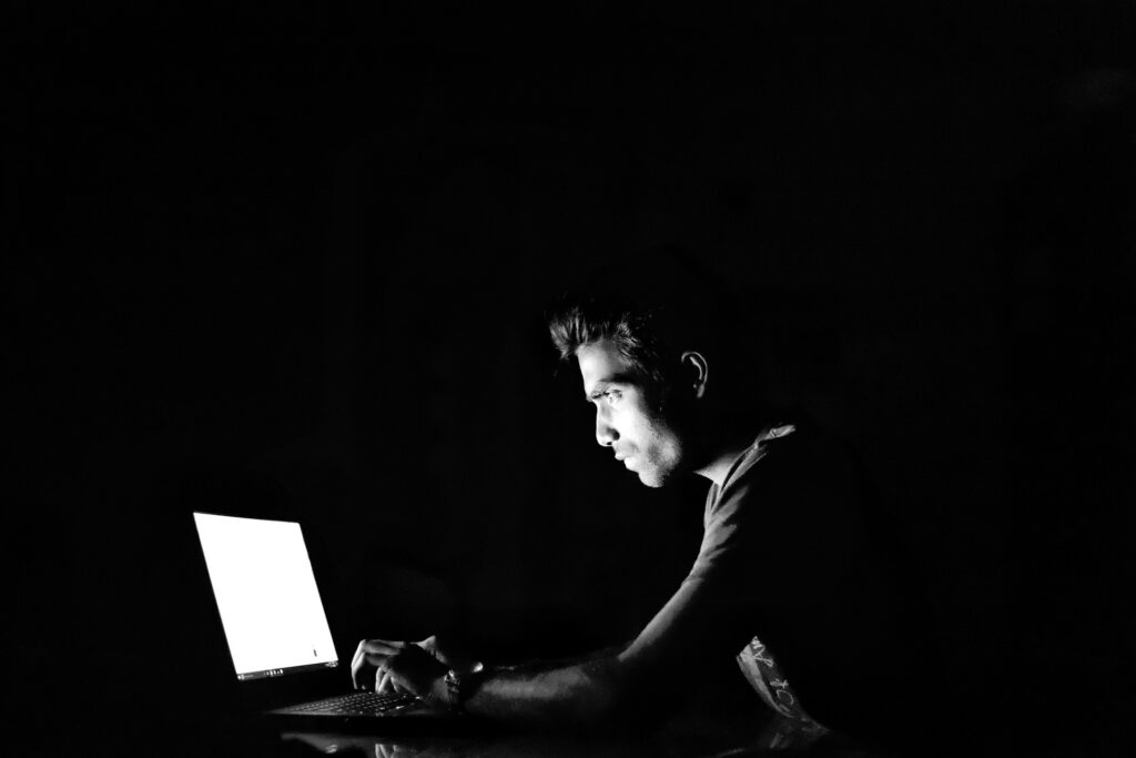 孤独にパソコンで仕事している男性の画像
