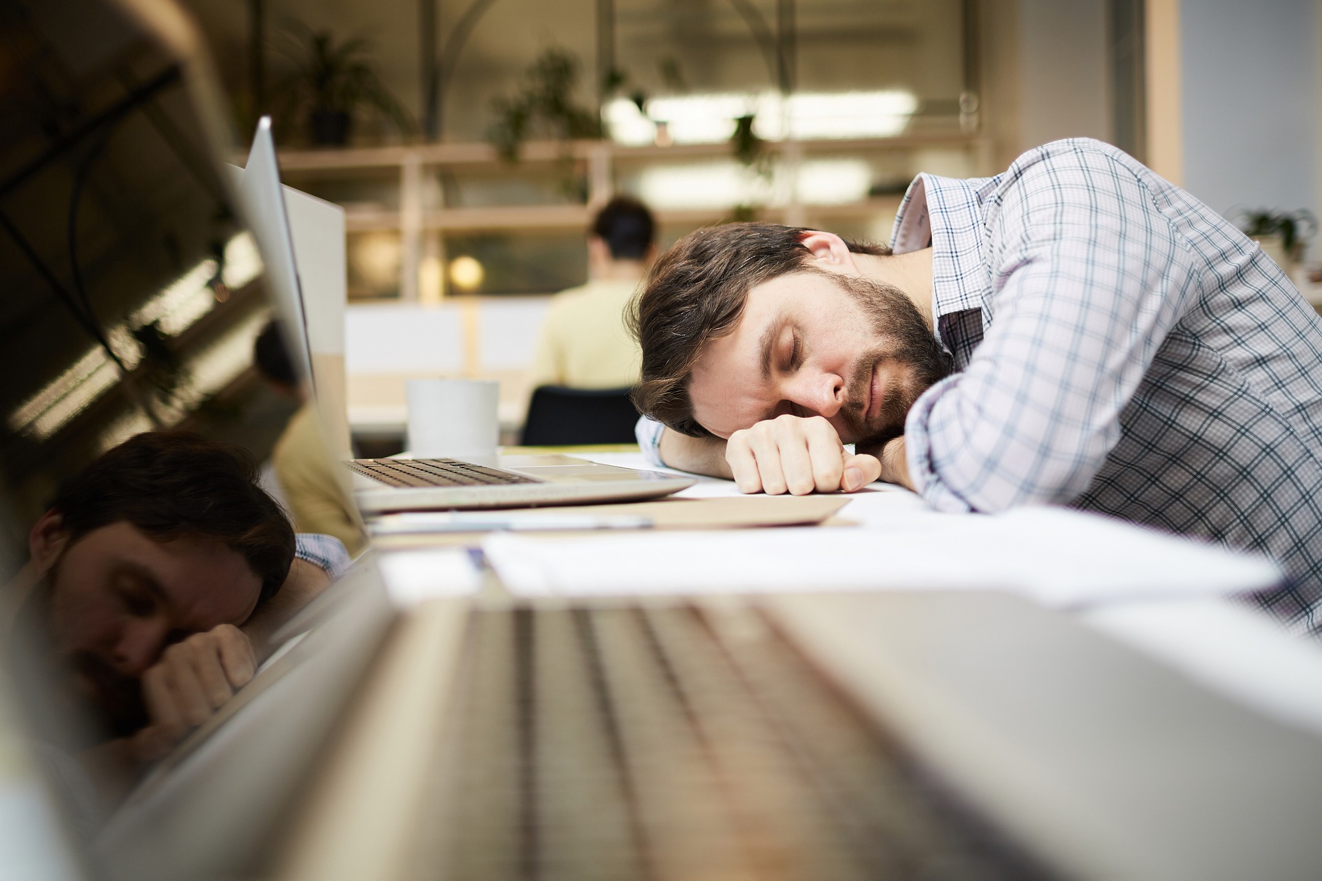 仕事中にパソコンの前で寝ている無能な男性の画像