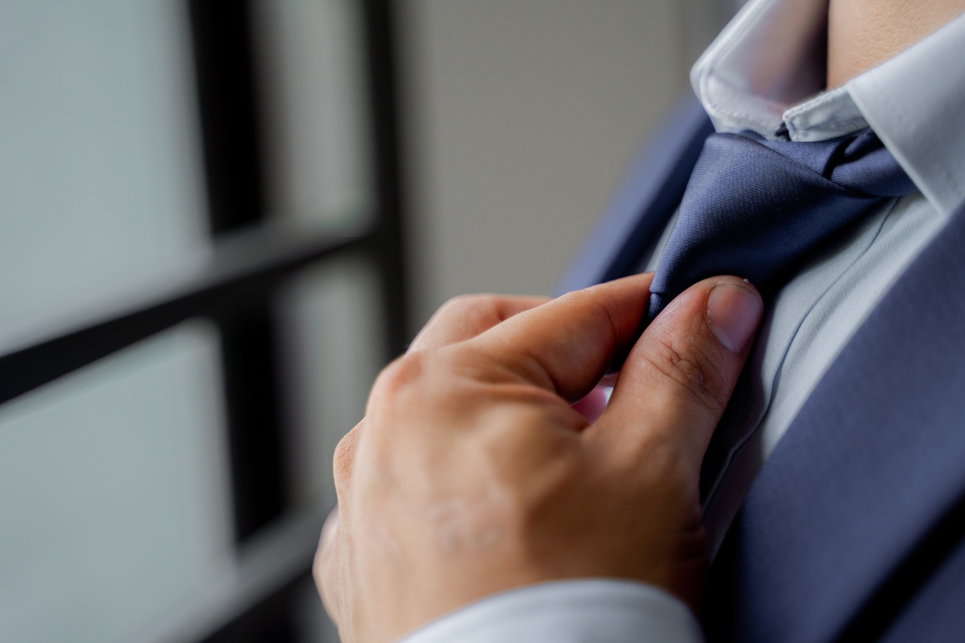 30代で仕事を辞めて転職活動のためにスーツのネクタイを締めている男性の画像